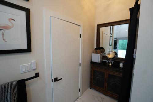 Bathroom with a white door, black towel rack, framed flamingo art, vanity with mirror, decorative baskets, and a partially visible window.