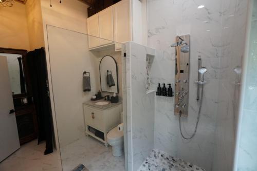 Modern bathroom with a glass-enclosed shower, stone tile floor, white sink, round mirror, and dark towels.Staniel Cay Vacation Rentals, One bedroom on the water with view of the Staniel Cay Yacht Club.