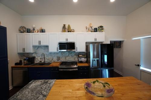 Modern kitchen with white upper cabinets, blue lower cabinets, stainless steel appliances, wooden countertops, and decorative items on top.