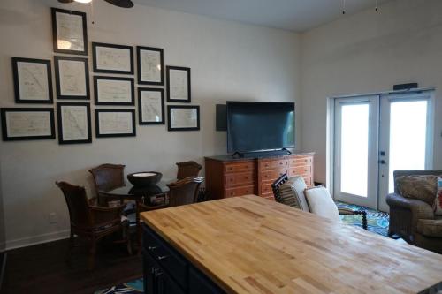 Vacation Rentals On Staniel Cay, Bahamas A living area with a kitchen island, a TV on a wooden dresser, a set of wicker chairs around a small table, and framed maps on the wall.