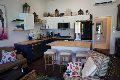 Cozy kitchen and living area with white and navy cabinets, wooden counters, bar stools, and decorative pillows.