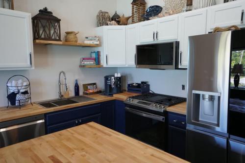 A modern kitchen with wooden countertops, stainless steel appliances, white and navy cabinets, and assorted decor items on shelves.