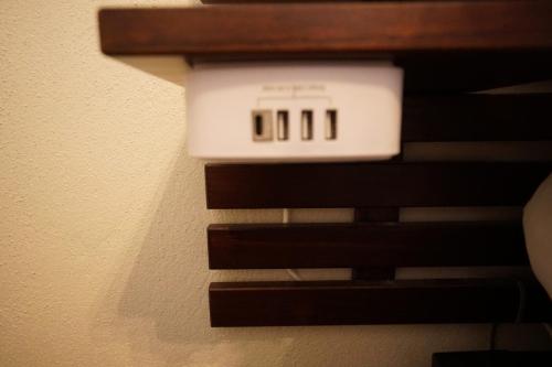 Wall-mounted USB charging station with three ports under a wooden shelf.