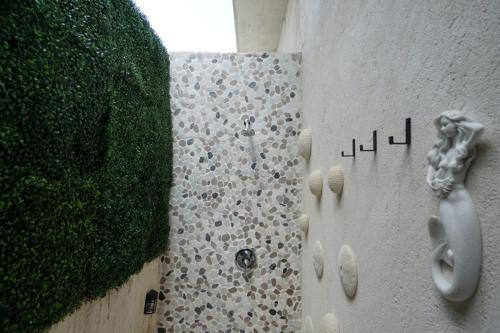 Outdoor shower with pebble tile, vertical greenery, and mermaid wall decor.