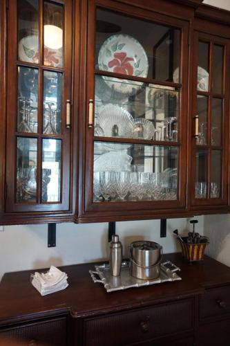 Vacation On Staniel Cay, BahamasWooden cabinet with glass doors displaying plates and glassware. Below, a table with a metal ice bucket, cocktail shaker, and napkins.