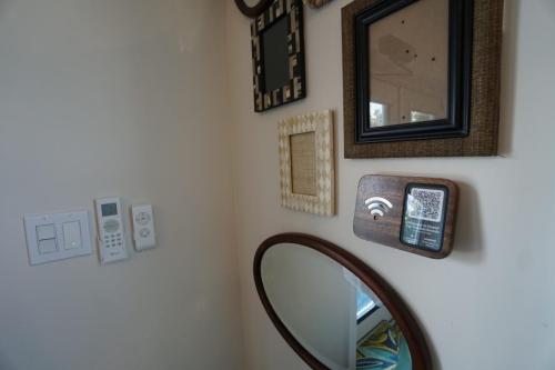 Staniel Cay Vacation Rentals, One bedroom on the water with view of the Staniel Cay Yacht Club. Wall with empty picture frames, mirror, light switches, a thermostat, and a sign featuring a Wi-Fi symbol and QR code.