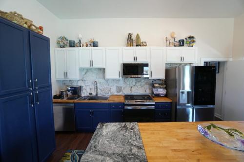 Staniel Cay Vacation Rentals, One bedroom on the water with view of the Staniel Cay Yacht Club. A modern kitchen with blue and white cabinets, stainless steel appliances, a marble backsplash, and a wooden countertop island.