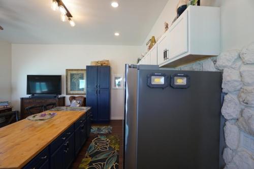 Staniel Cay Vacation Rentals, One bedroom on the water with view of the Staniel Cay Yacht Club. Kitchen with wooden island, blue cabinets, stainless steel refrigerator, TV on a dresser, and tropical-themed rug.